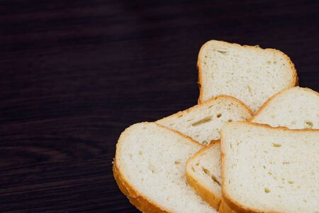 Sliced white bread on a brown background. Fresh homemade bread made from white flour. Pieces of...