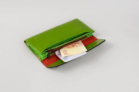 Big green wallet with money on a brown background. Ukrainian hryvnia. Money in the wallet. Womens...