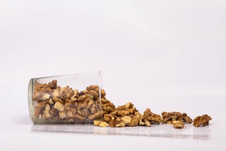 Walnuts in a glass. Scattered peeled nuts. Glass jar with peeled walnuts.