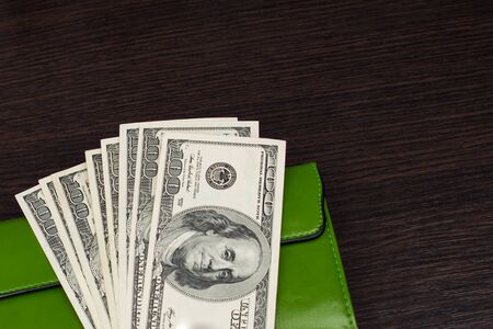 Wallet with money on a brown background. A pack of dollars in your wallet. Banknotes one hundred...