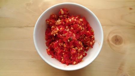 Pile of Fresh Red Hot Chili in the white bowl on the wooden tableの写真素材