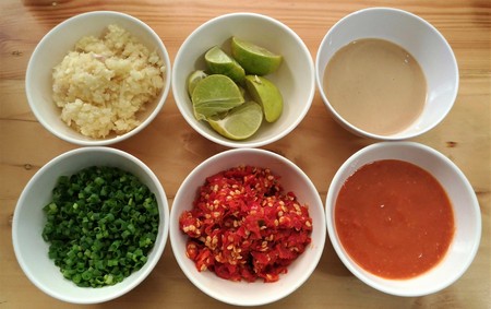 Thai ingredient include gralic, lemon, chili, sauce, onion in the white bowls on the wooden table.の写真素材