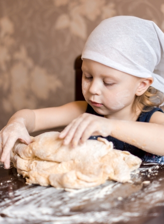 child knead the dough in a kerchiefの写真素材