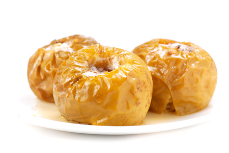 baked apples in a white plate on a white backgroundの写真素材