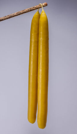 Hanging handmade joined candles on white backgroundの写真素材