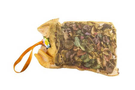 Orange mesh bag of dried flowers on a white background.の写真素材
