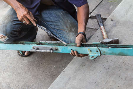 Closeup on man's hand, repair the Iron door. working outdoors.の写真素材