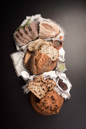 Different types of bread on a black background. See from above. Freshly baked wheat bread loaf breakfast tableの写真素材