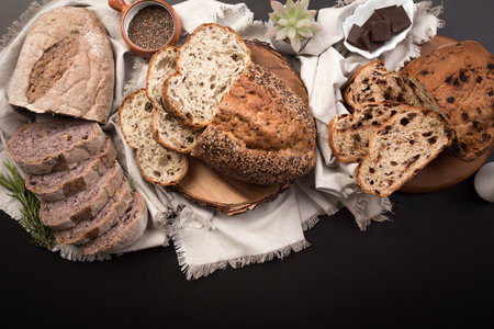Variety of breads on a black background. top view. Freshly baked wheat bread loaf breakfast table