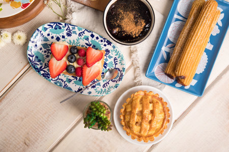 Top view of pastries with berries and coffee on wooden background. Assorted peruvian desserts peru...