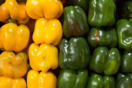 Green and yellow bell peppers on display in a market. Select focus.の写真素材