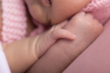 Close-up of a newborn baby's hand holding mother's fingerの写真素材