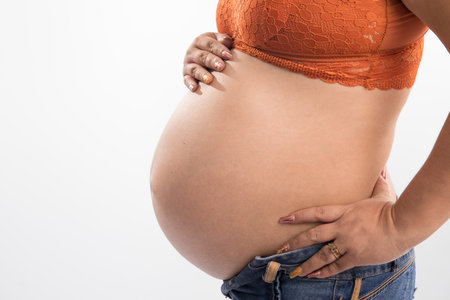 Pregnant woman touching her belly, isolated on white background.の写真素材