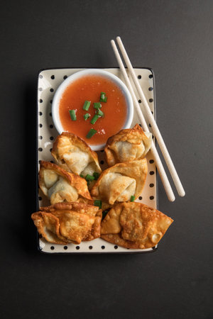Fried Dumplings with sauce and chopsticks on a black background