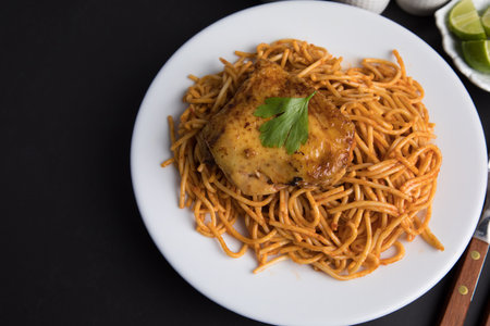 Spaghetti with chicken and tomato sauce on white plate on black backgroundの写真素材