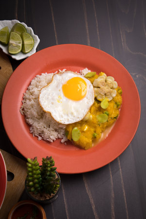 Locro peruvian food Fried egg in curry sauce with rice and vegetables on a plateの写真素材