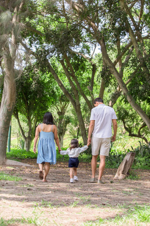 Happy family walking in the park. Parents and child having fun outdoors.の写真素材