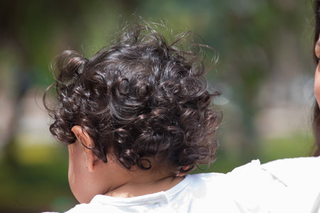 Back view of little girl with long curly hair in the park.の写真素材