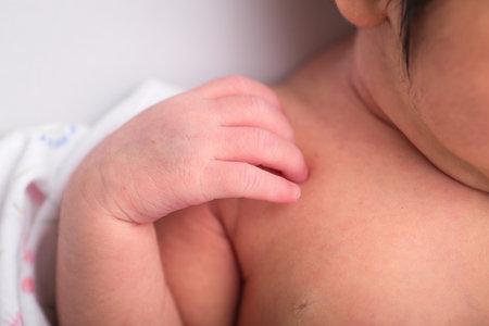 Close-up of a newborn baby's hand touching his mother's breastの写真素材