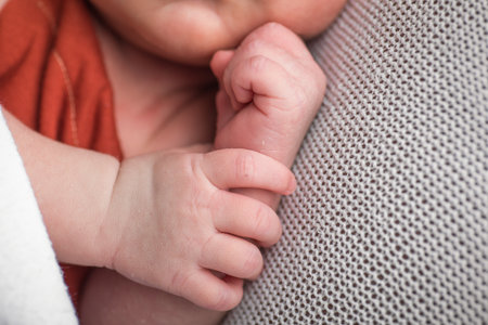 Newborn baby's hands close up on a knitted background.