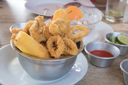 Mixed chicharrÃ³n Fried shrimp in a bowl on wooden table, peruvian food