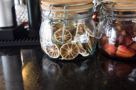 Dried fruits in a glass jar on a black countertop.の写真素材