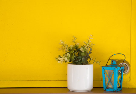 Vintage lamp and flower in vase on yellow wall background.の写真素材
