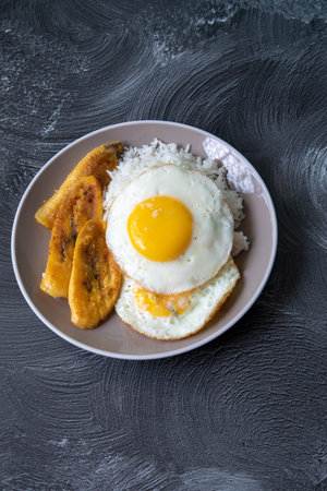 Fried egg with banana and rice in a plate on a dark backgroundの写真素材