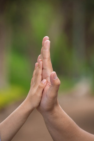 Hands of father and son praying together in the park. Concept of faith and spirituality.