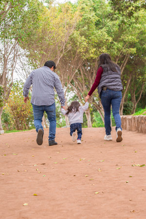 Happy family walking in the park. Father, mother and daughter having fun together.