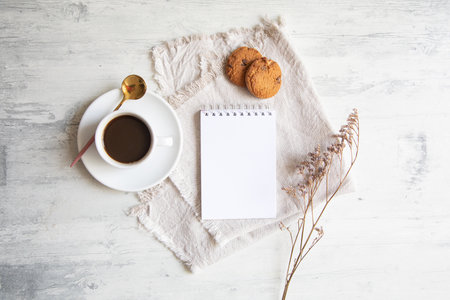 Cup of coffee, notepad and oatmeal cookies on white wooden backgroundの写真素材
