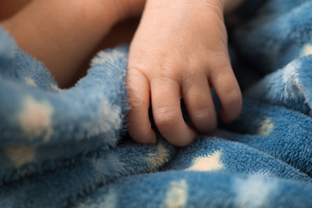 Newborn baby's hand on blue blanket, closeup. Baby care conceptの写真素材