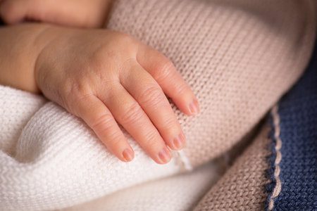 Close-up of newborn baby's hand holding a knitted blanketの写真素材