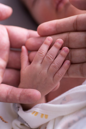 Close up of hands of mother and baby, shallow depth of fieldの写真素材