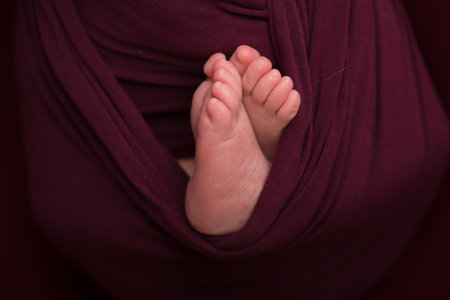 Feet of a newborn baby wrapped in a purple cloth. Shallow depth of field.の写真素材