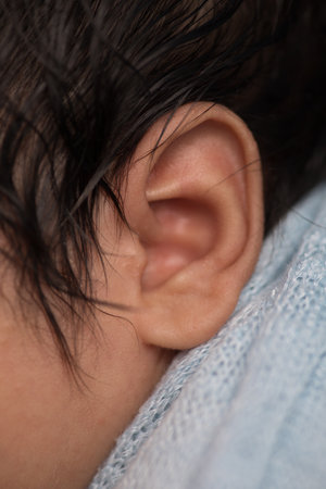 Close-up of a child's ear in a blue scarf.の写真素材