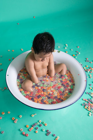 Cute asian baby boy taking a bath with colorful cereal balls.の写真素材