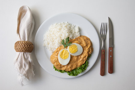 Eggs in curry sauce with rice and fork on white backgroundの写真素材