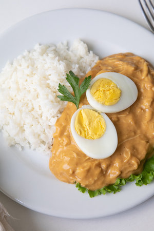 Aji de gallina peruvian cuisine traditional Peru food Eggs with curry sauce and rice on a white plate.の写真素材