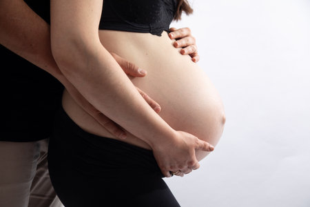 Pregnant woman with hands on her belly on a white backgroundの写真素材
