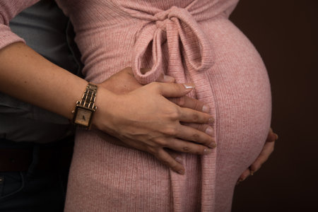 Pregnant woman holding her hands on her belly, close upの写真素材