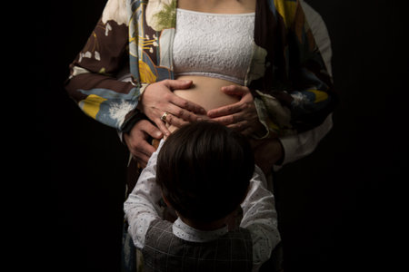 Young pregnant woman with her husband in the studio on a black backgroundの写真素材