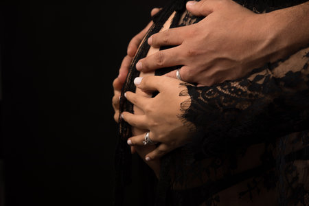 Close up of a couple's hands embracing each other on black backgroundの写真素材