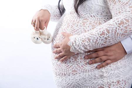 Pregnant woman holding baby shoes on white background, closeupの写真素材