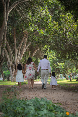 Back view of happy family walking in the park on summer day.の写真素材