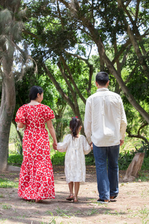 Asian family walking in the park and holding hands. Back view.