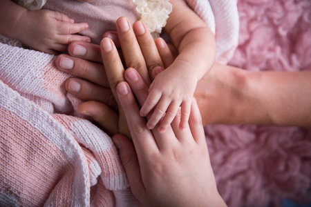 Close up of hands of a mother and her baby on pink backgroundの写真素材