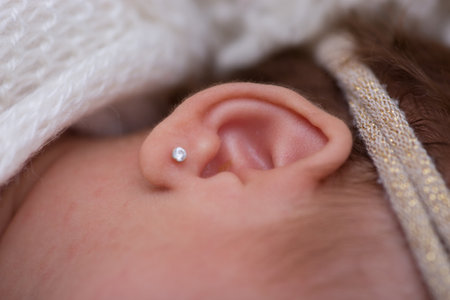 Close-up of a newborn baby's ear with earring.