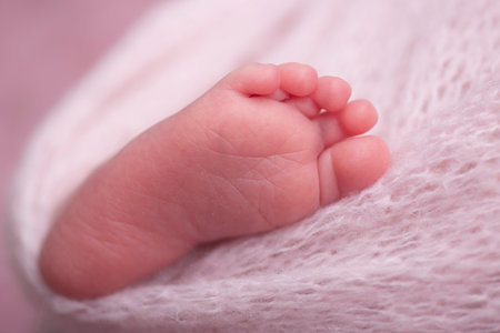 Newborn baby feet on a pink background, close-up.の写真素材