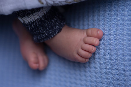 Newborn baby feet on blue blanket close-up, shallow depth of field